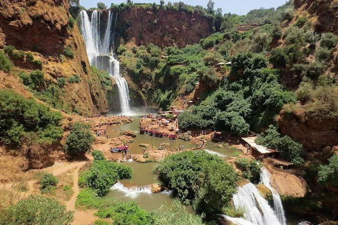 Vue panoramique des cascades d'Ouzoud jaillissant au milieu des falaises rousses et de la végétation luxuriante au Maroc.