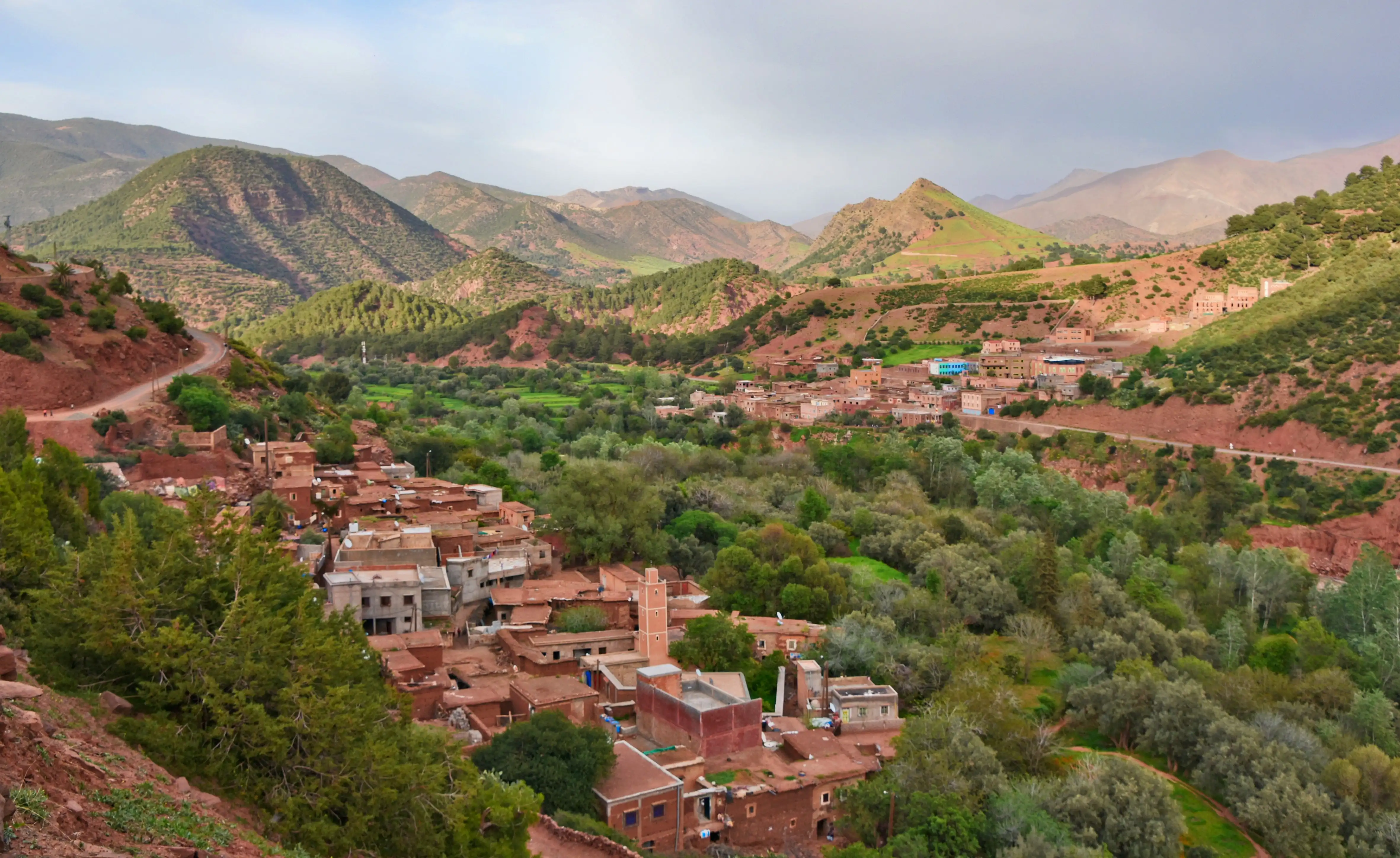 Village berbère traditionnel en terre ocre niché dans la vallée verdoyante de l'Ourika